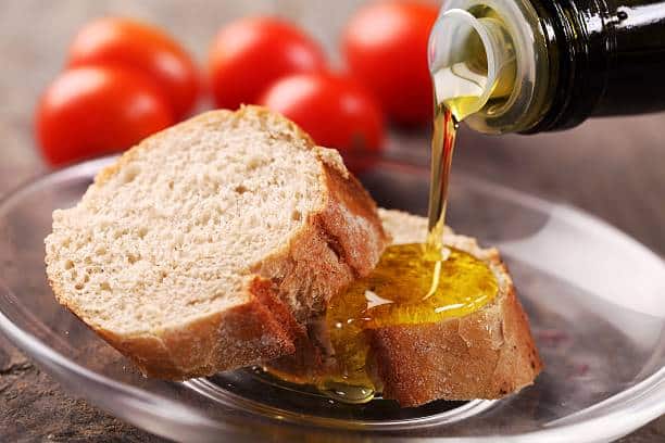 dos tostadas de pan a las que les están echando aceite